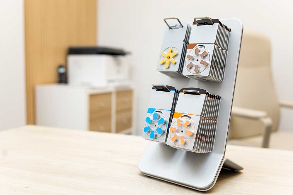 Display stand of color-coded hearing aid battery packs on a clinic desk, for battery life tips from My Hearing Aid Place in Richmond Hill, GA